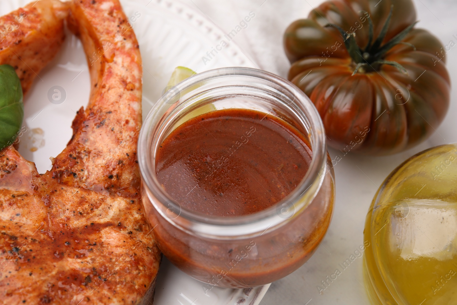 Photo of Fresh marinade, cooked fish and other products on white marble table, closeup