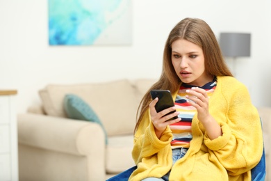 Concentrated young woman playing online lottery using smartphone at home