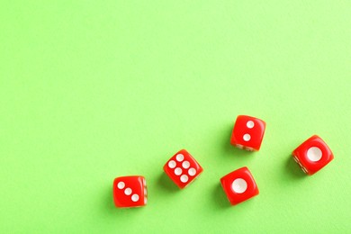 Photo of Many red game dices on green background, flat lay. Space for text