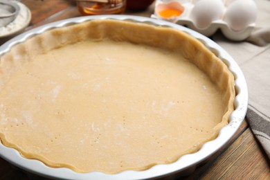 Photo of Raw dough for traditional English apple pie on wooden table, closeup
