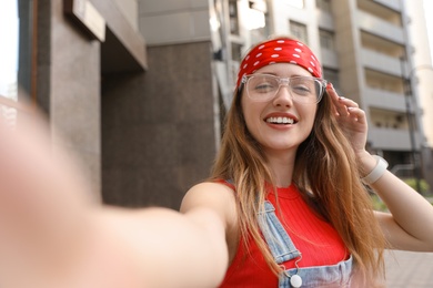 Photo of Beautiful young woman in stylish  headband taking selfie outdoors