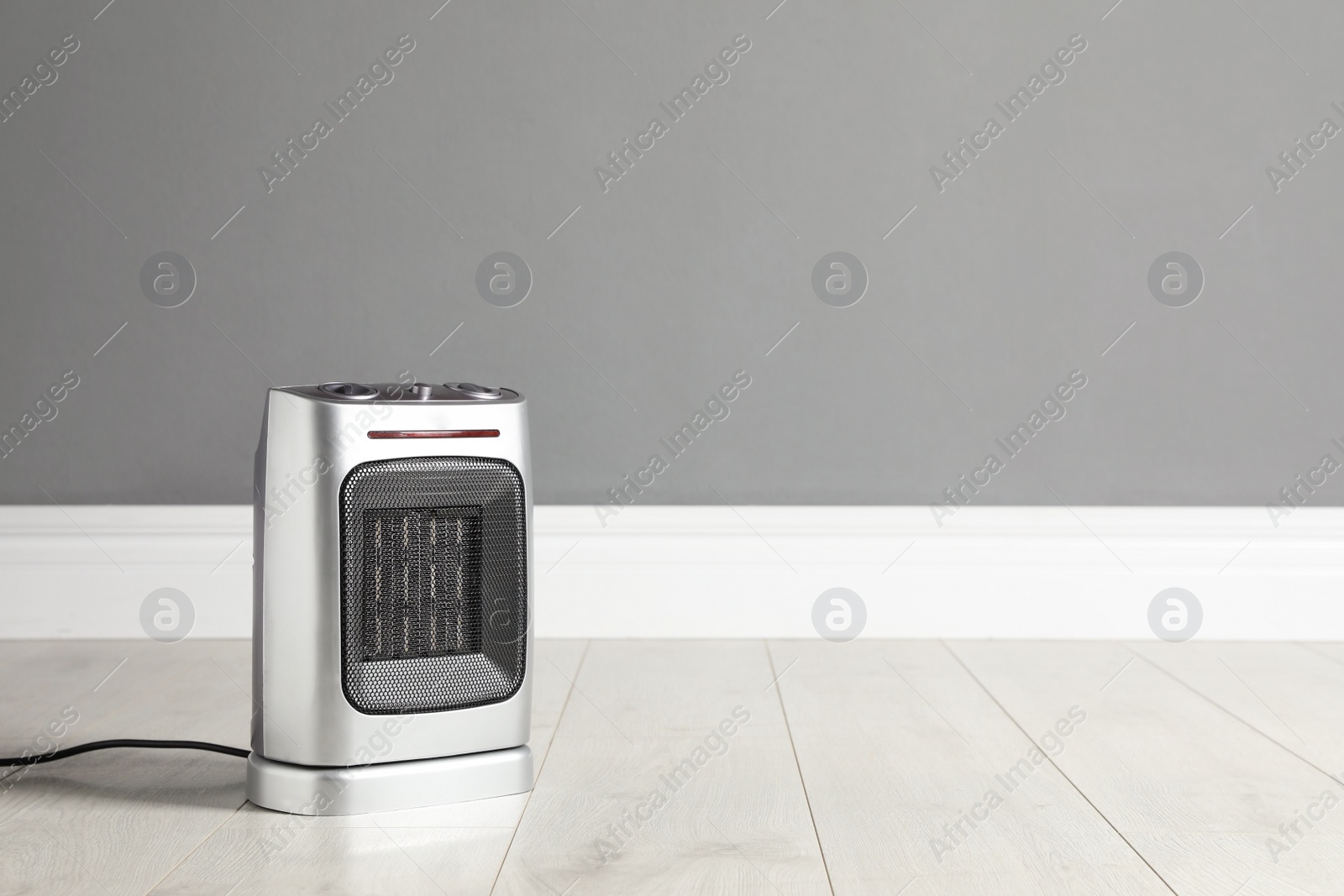 Photo of Modern electric fan heater on floor in room, space for text