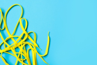 Yellow shoelaces on light blue background, flat lay. Space for text