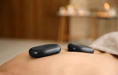 Man receiving hot stone massage in spa salon, closeup. Space for text