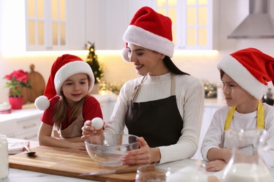 Photo of Mother with her cute little children making Christmas cookies in kitchen