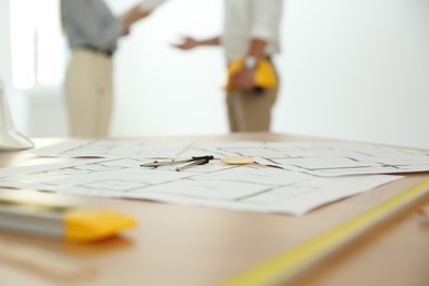 Colleagues in office, focus on table with construction drawings and tools