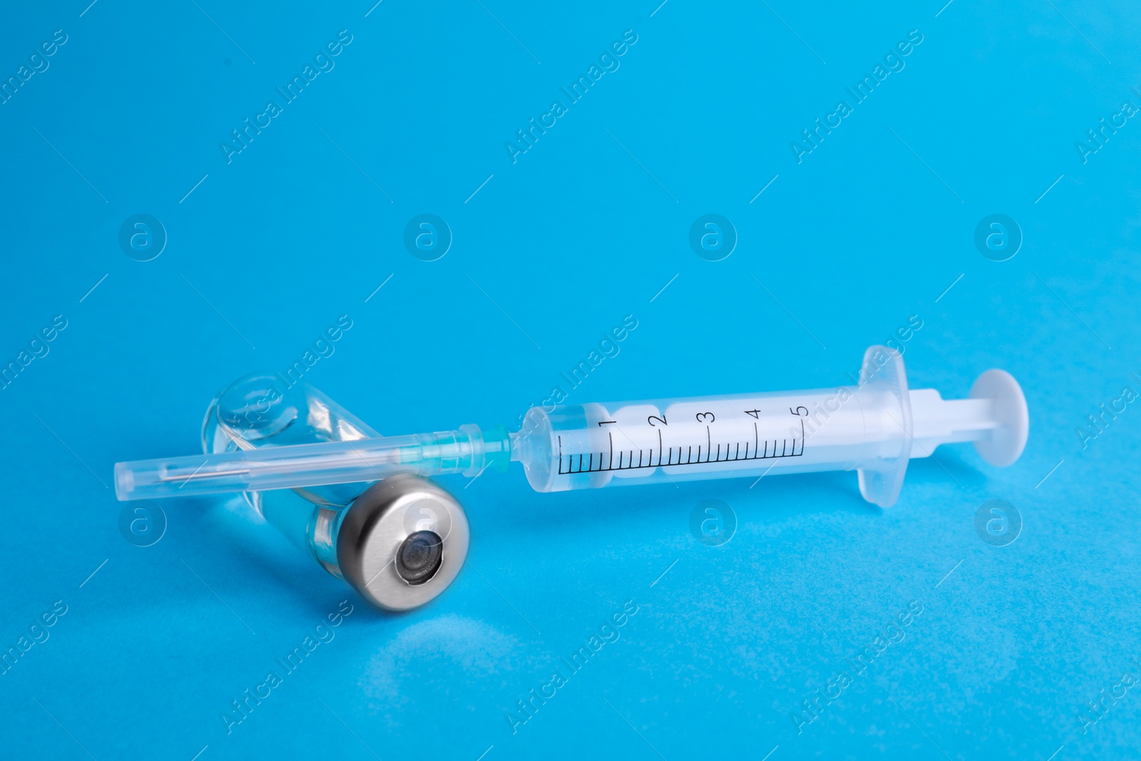Photo of Disposable syringe with needle and vial on light blue background
