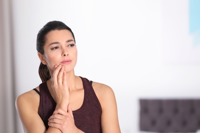 Young woman with sensitive teeth indoors. Space for text