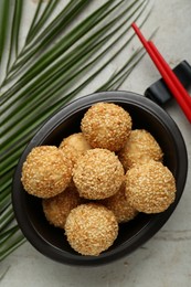 Photo of Delicious sesame balls and green leaf on textured table, flat lay