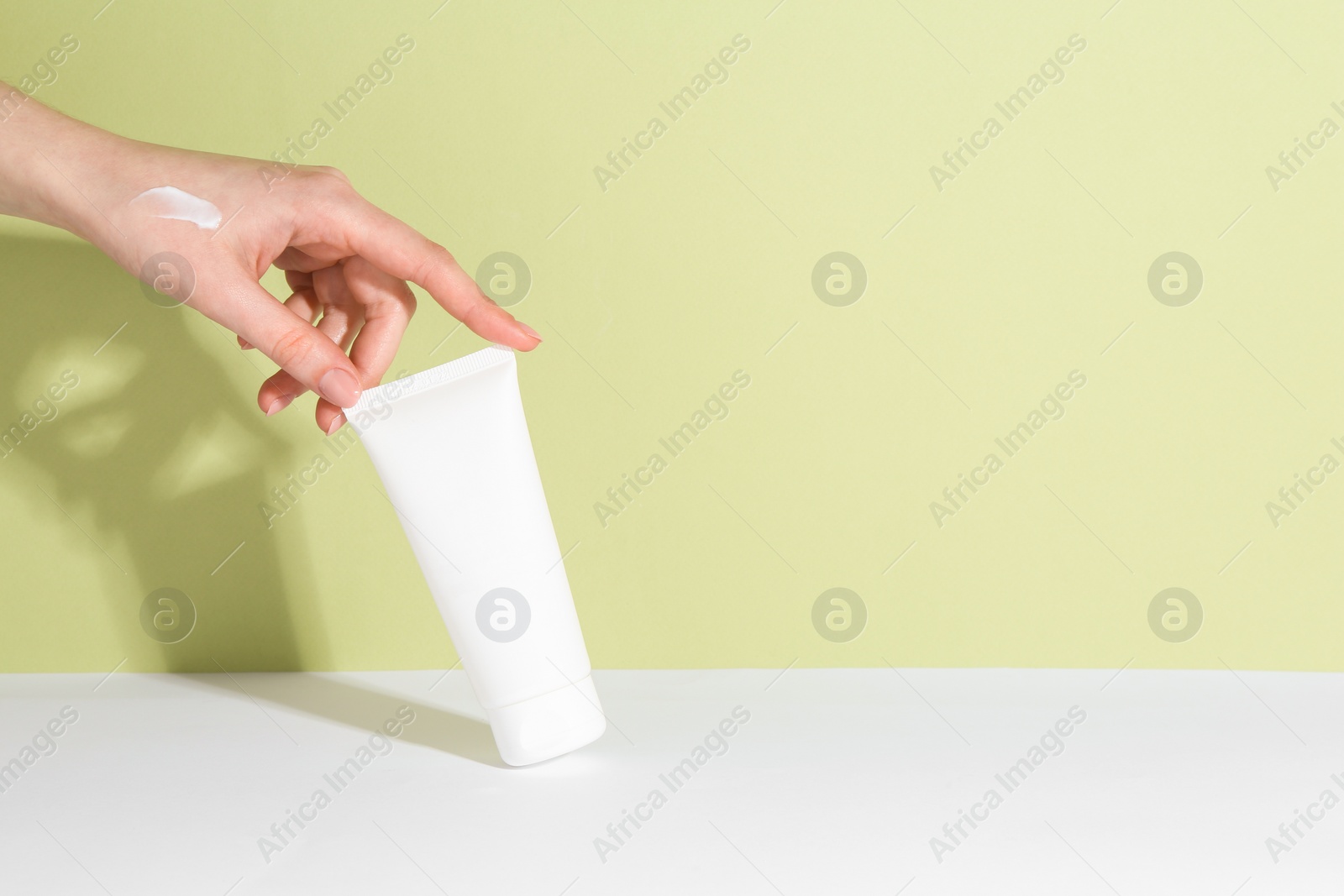 Photo of Woman with tube of cream on color background, closeup. Space for text