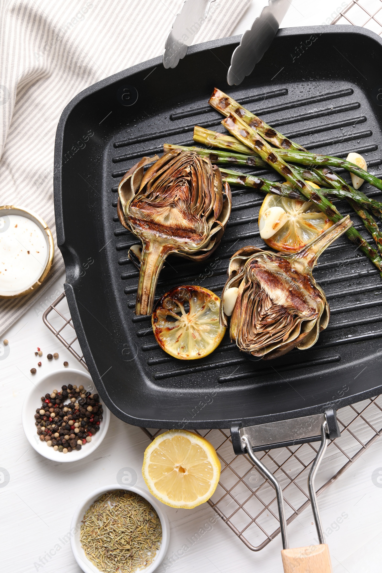 Photo of Tasty grilled artichokes served on white wooden table, flat lay