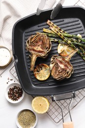 Tasty grilled artichokes served on white wooden table, flat lay