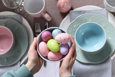 Photo of Woman setting table for festive Easter dinner at home, top view