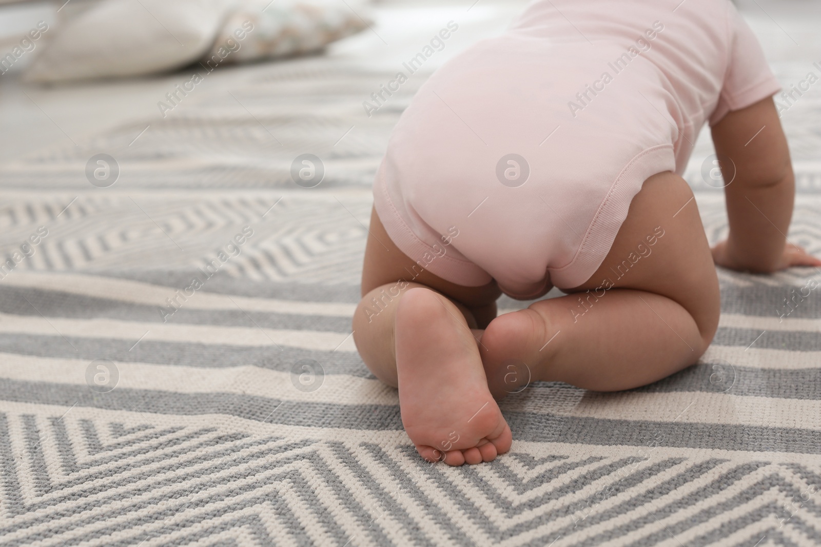 Photo of Baby crawling on floor at home, closeup