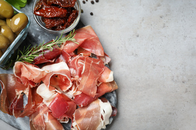 Photo of Tasty prosciutto served on light grey table, flat lay. Space for text