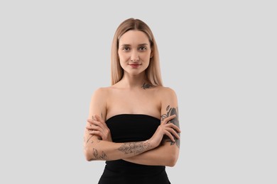 Photo of Portrait of beautiful tattooed woman on light background