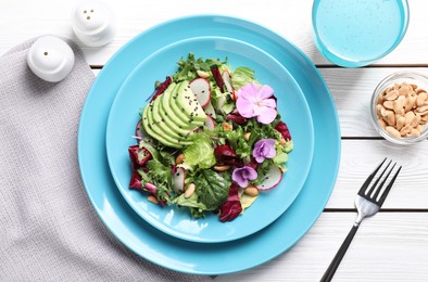 Fresh spring salad with flowers served on white wooden table, flat lay