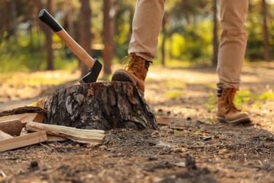 Photo of Man near tree stump with axe in forest, closeup of legs