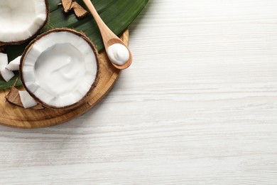 Photo of Ripe coconut and cream on white wooden table, flat lay. Space for text