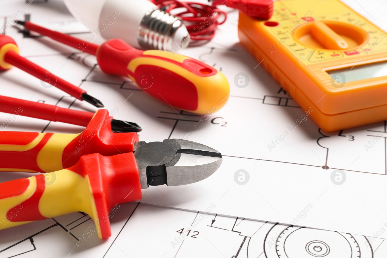 Photo of Set of electrician's tools and accessories on paper sheets, closeup