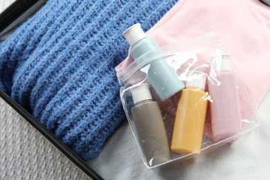 Photo of Plastic bag of cosmetic travel kit in suitcase, top view