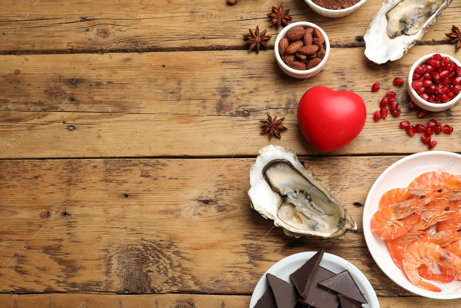 Photo of Natural aphrodisiac. Different food products and heart model on wooden table, flat lay. Space for text