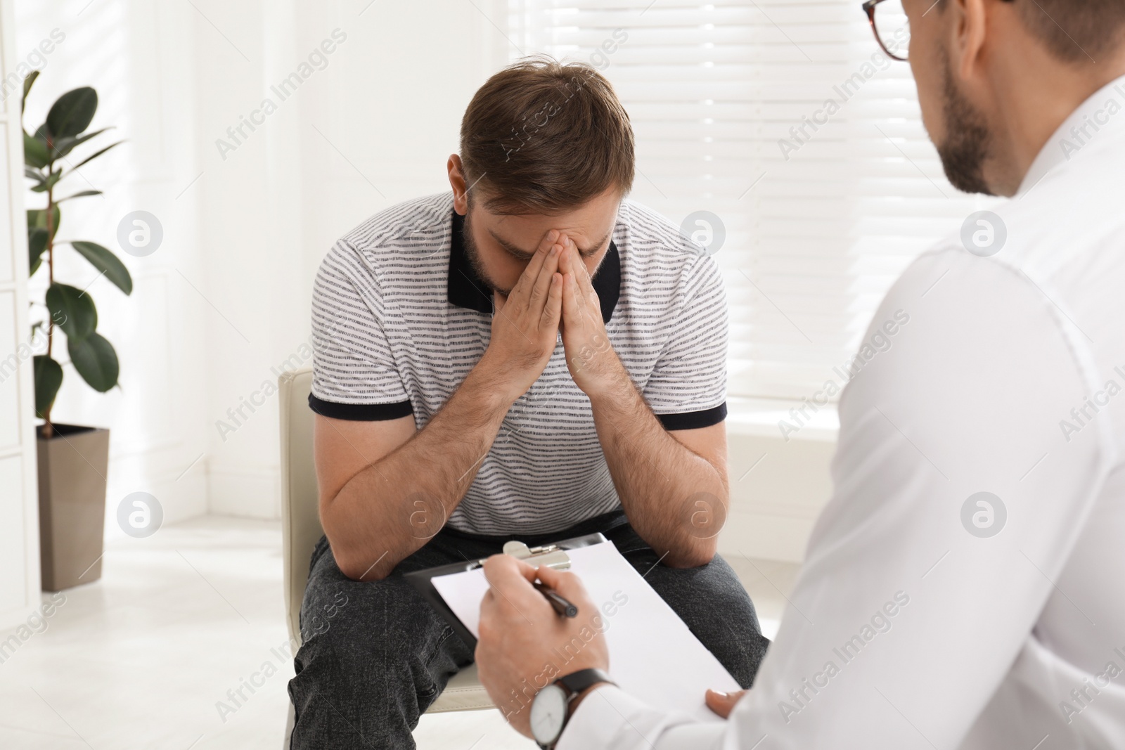 Photo of Psychotherapist working with drug addicted young man indoors