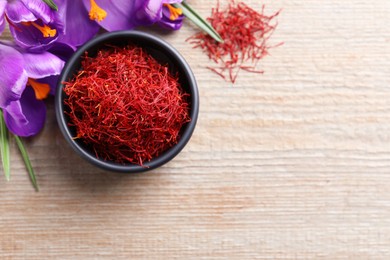 Photo of Dried saffron and crocus flowers on wooden table, flat lay. Space for text