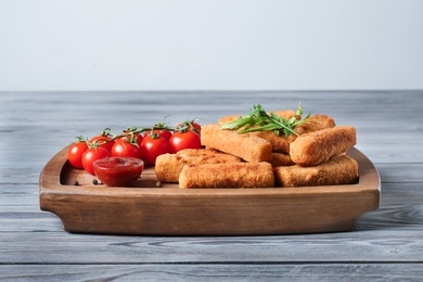 Board with cheese sticks, sauce and tomatoes on table