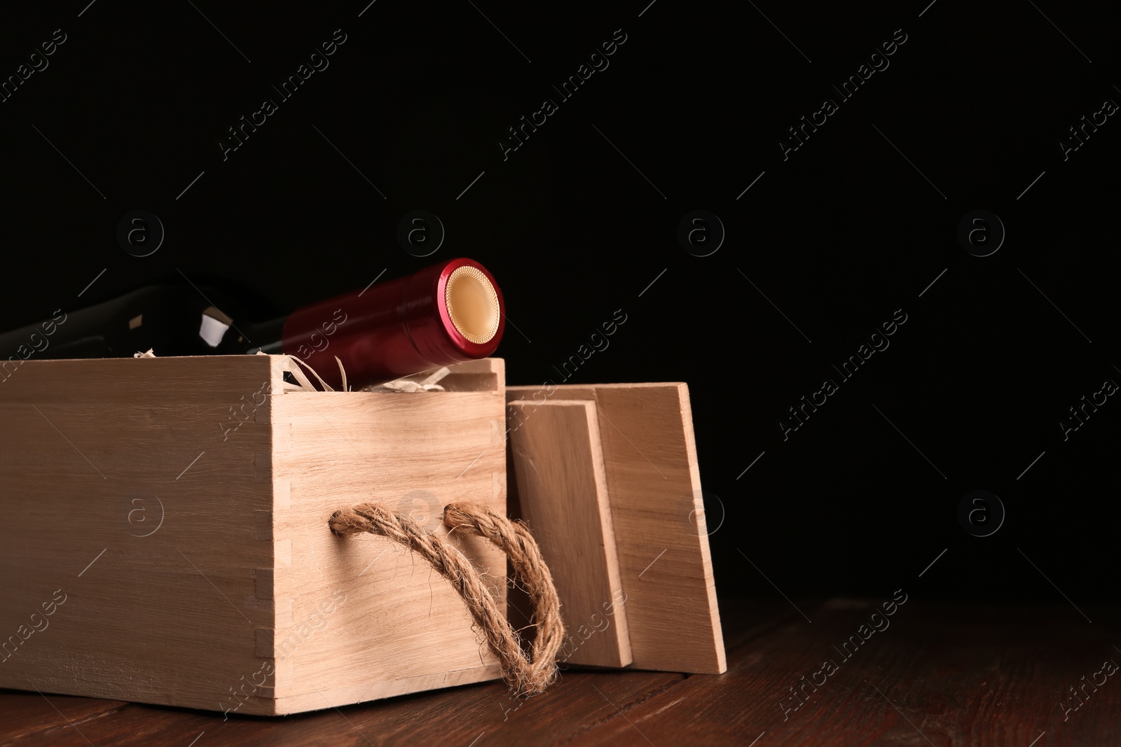 Photo of Open wooden crate with bottle of wine on table, space for text