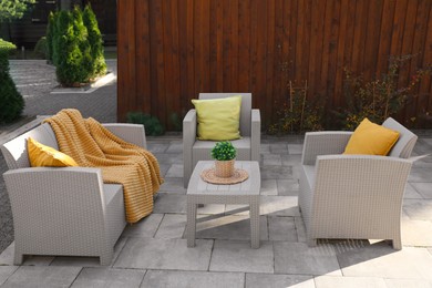 Photo of Beautiful rattan garden furniture, soft pillows, blanket and houseplant in backyard