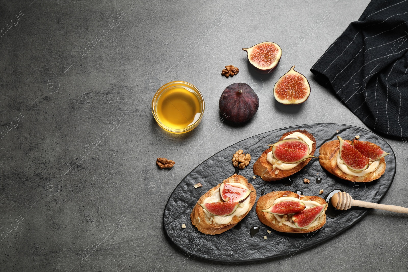 Photo of Bruschettas with ripe figs and cream cheese served on grey table, flat lay. Space for text