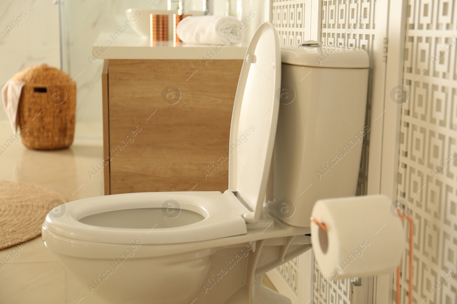 Photo of Toilet bowl near wooden screen in modern bathroom interior