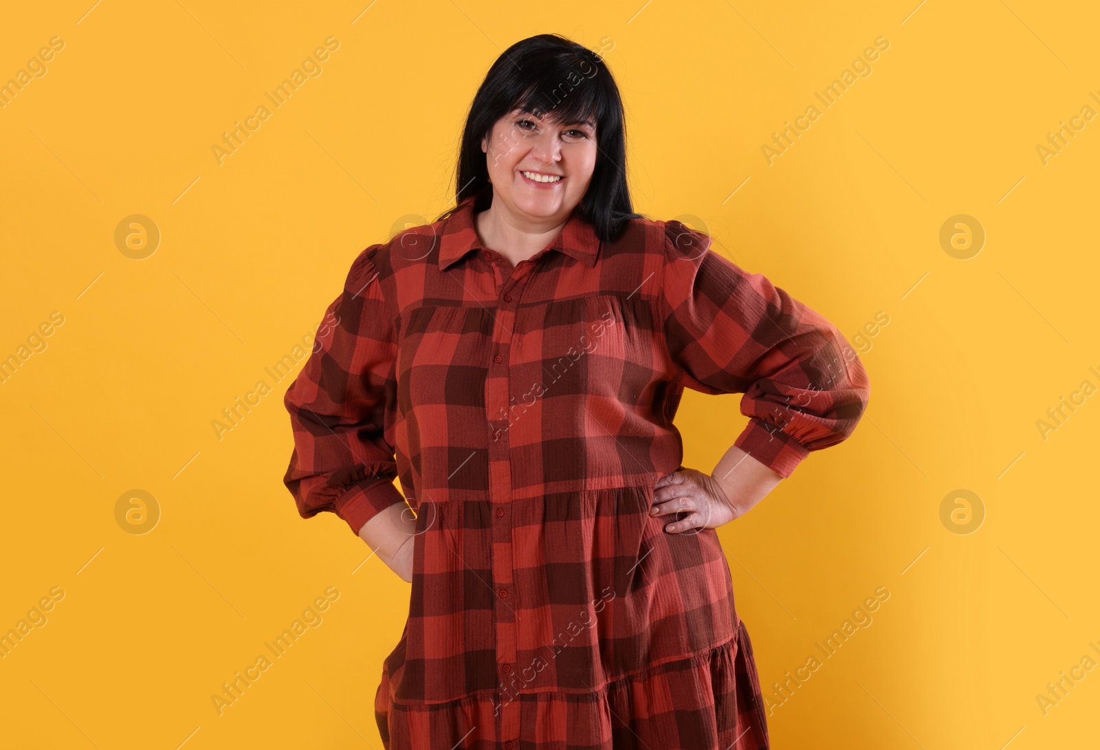 Photo of Beautiful overweight mature woman with charming smile on yellow background