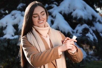 Photo of Woman applying moisturizing cream on hands in winter