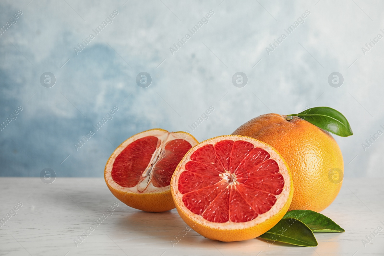 Photo of Fresh tasty grapefruits on table against color background. Space for text