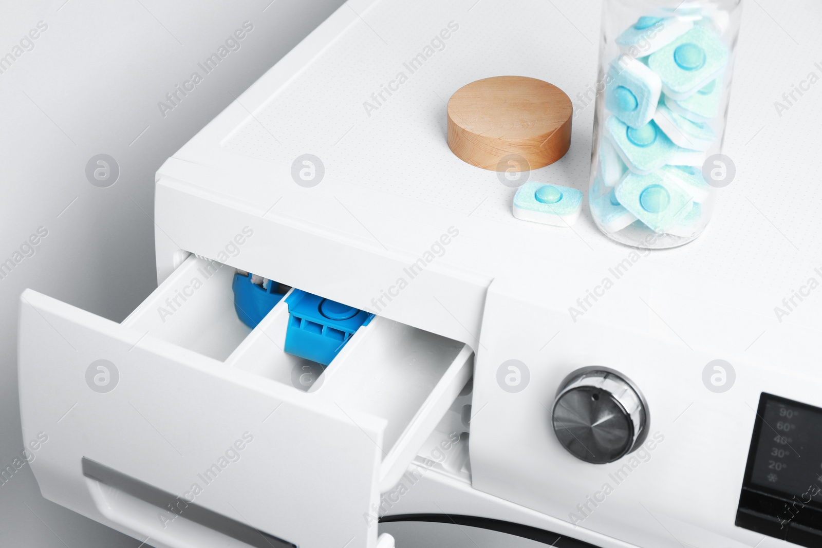 Photo of Woman putting water softener tablet into washing machine, closeup