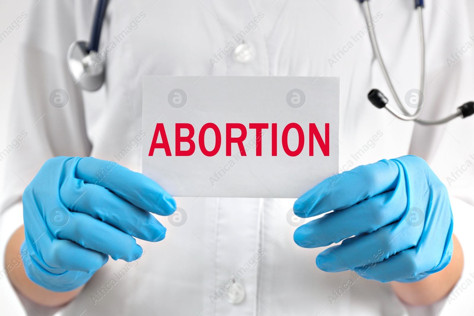 Image of Doctor holding paper card with word Abortion, closeup