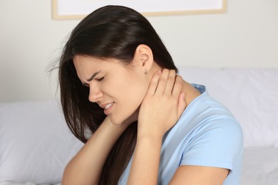 Photo of Young woman suffering from neck pain indoors