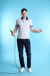 Photo of Handsome man in casual clothes posing with microphone on color background