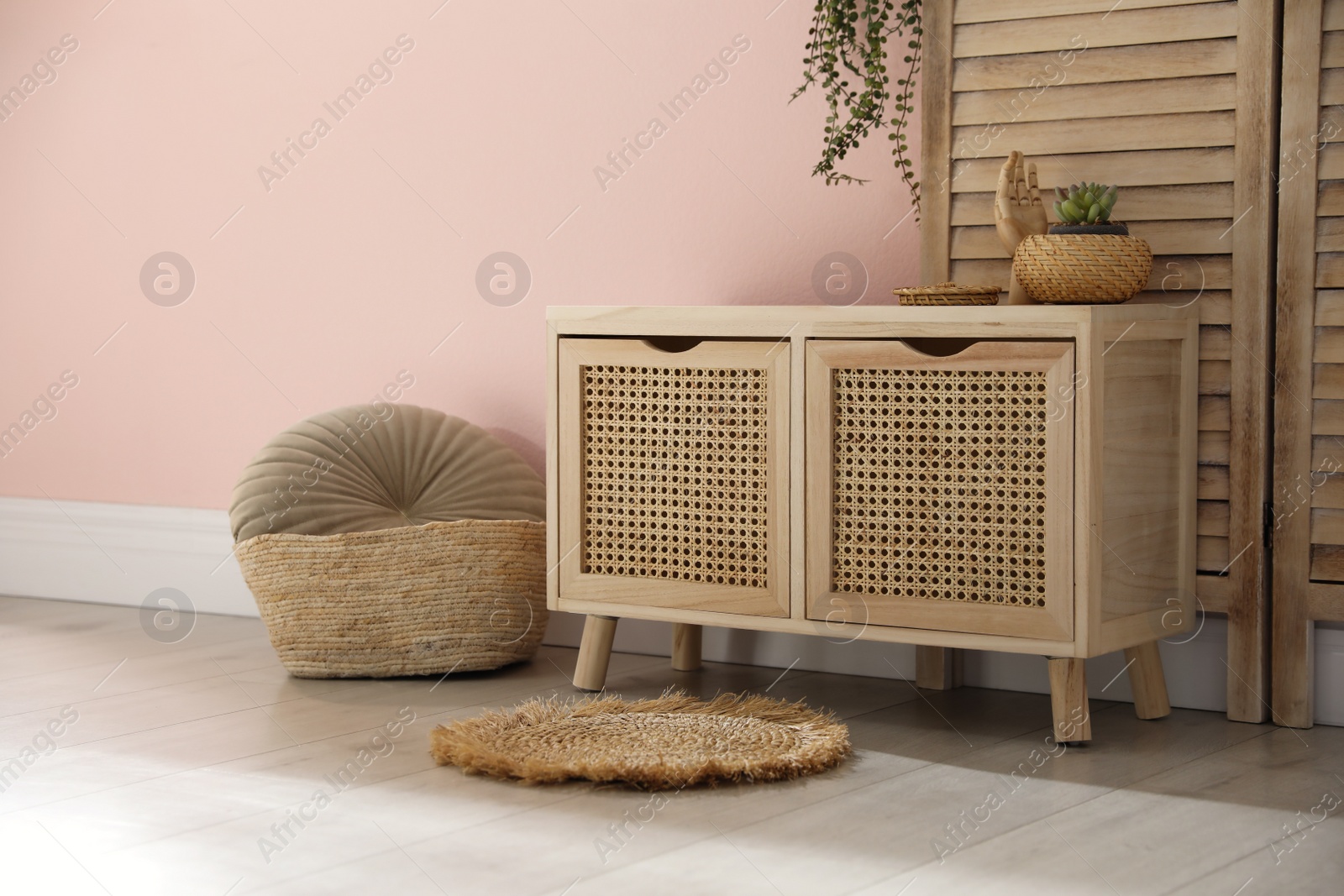 Photo of Wooden commode near pink wall in room. Interior design