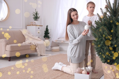 Photo of Happy mother with her cute son decorating Christmas tree together at home