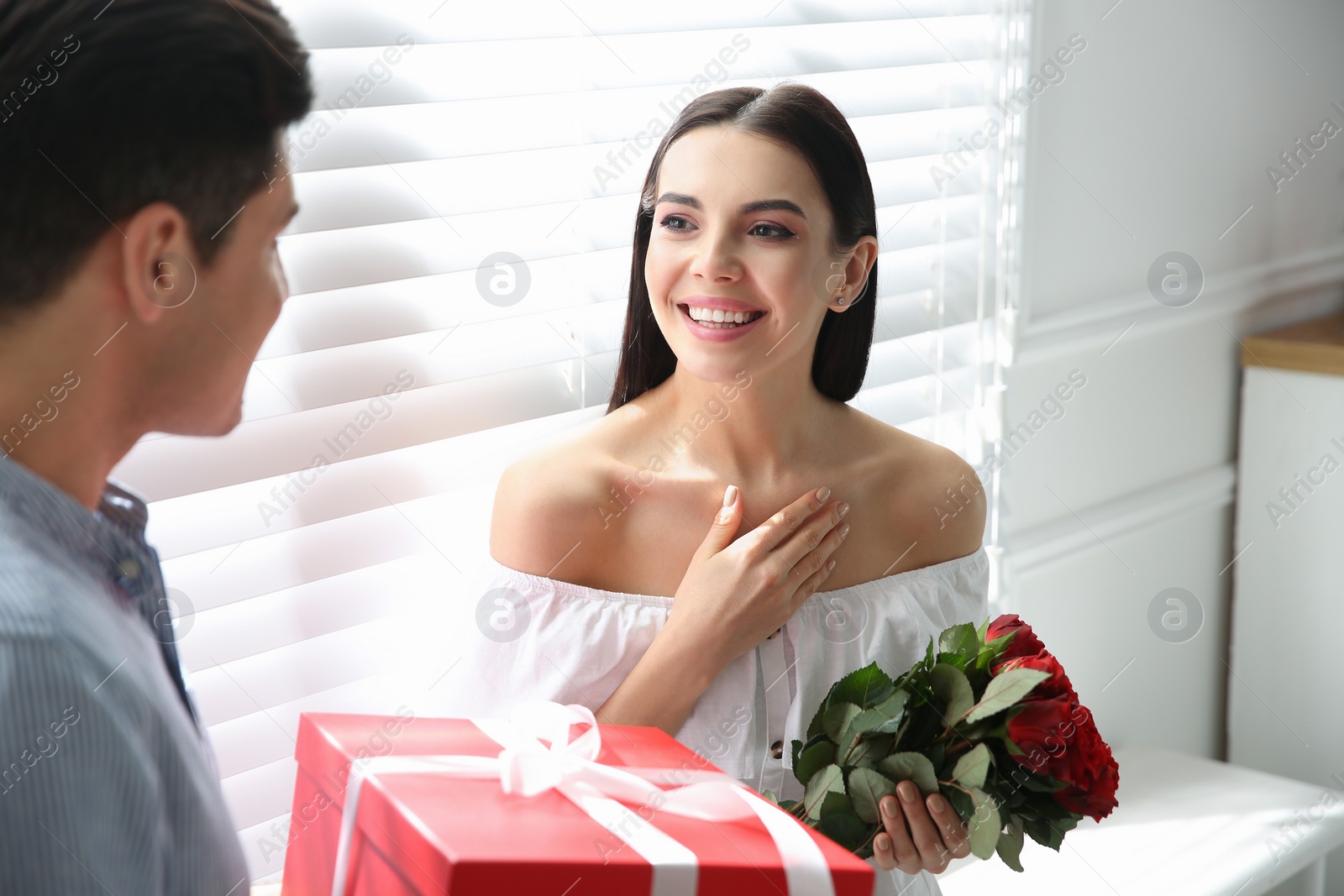 Photo of Man presenting gift to his beloved woman at home. Valentine's day celebration