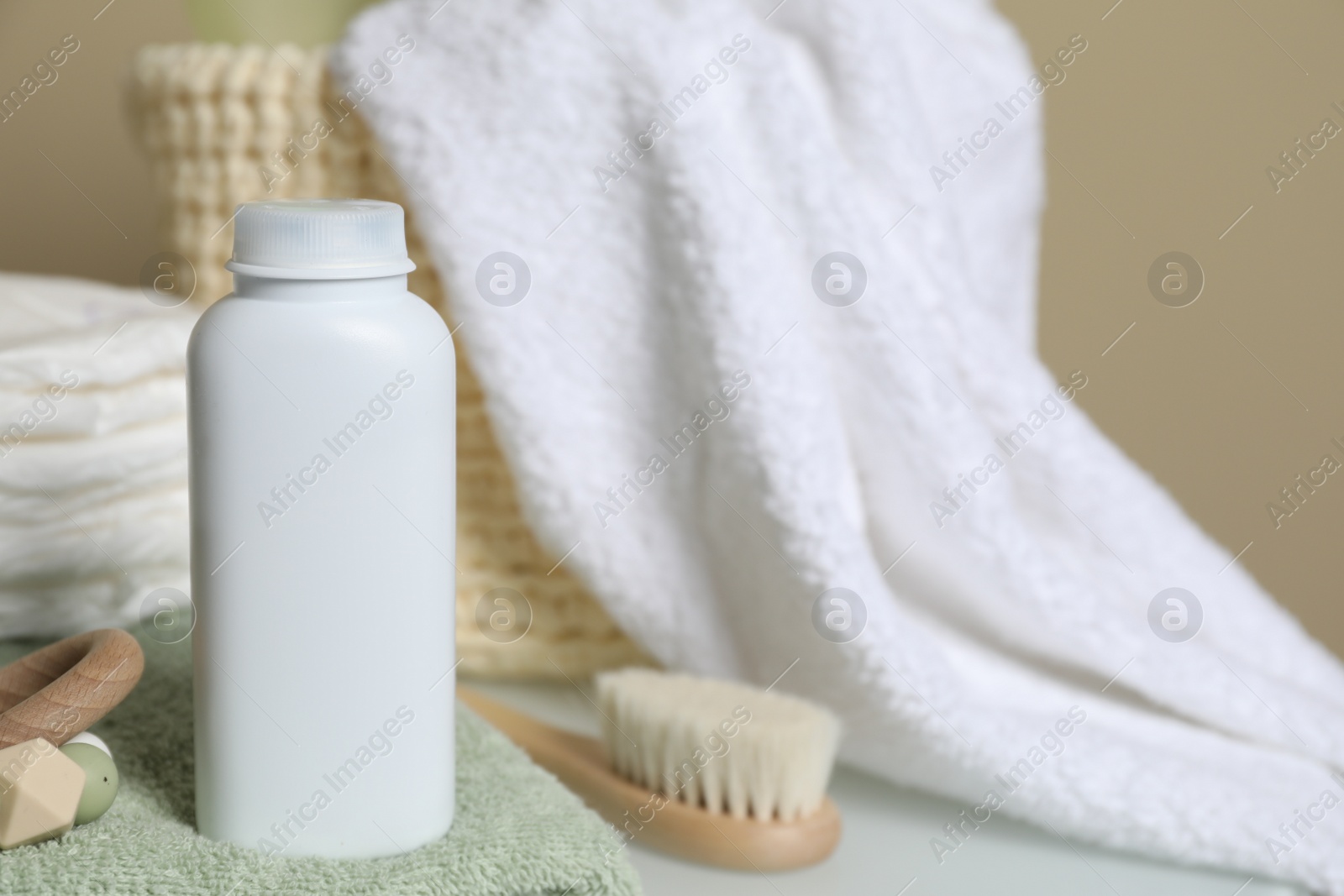 Photo of Bottle of dusting powder, toy and accessories on table, space for text. Baby cosmetic product