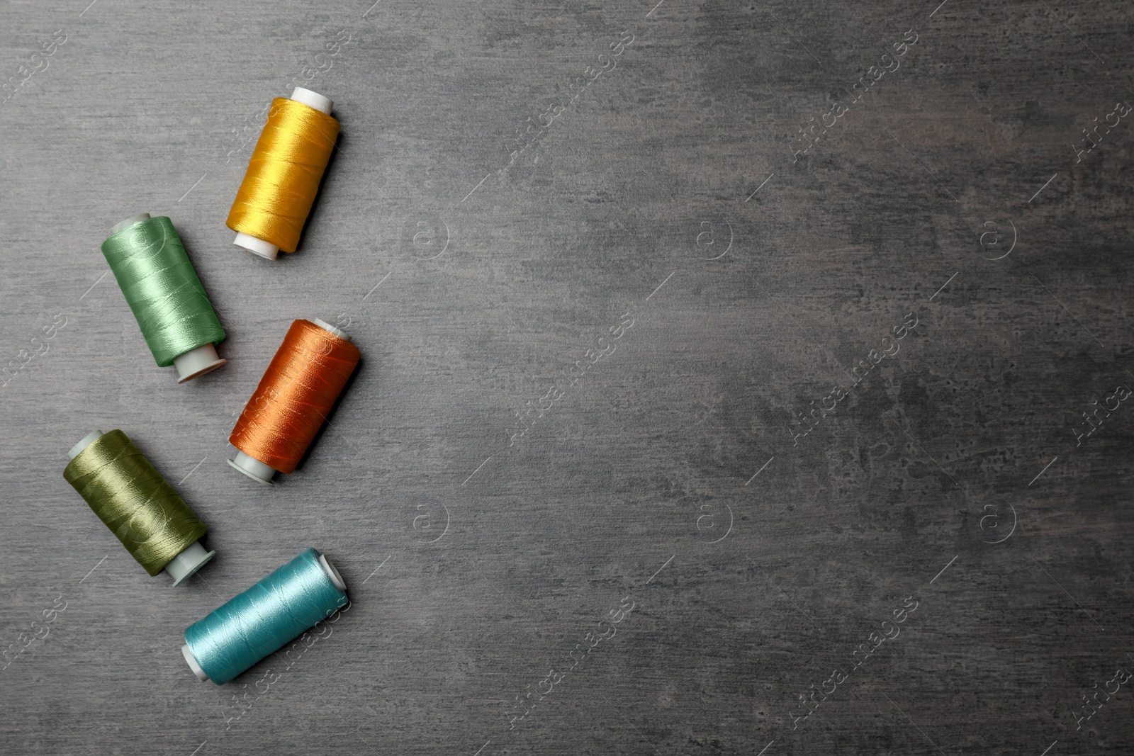 Photo of Color sewing threads on gray background, top view