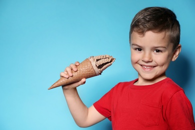 Photo of Adorable little boy with delicious ice cream against color background, space for text