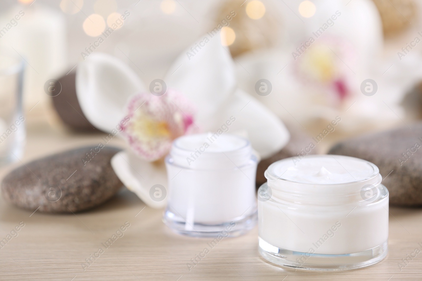 Photo of Beautiful composition with cosmetic products, spa stones and flowers on table, closeup. Space for text
