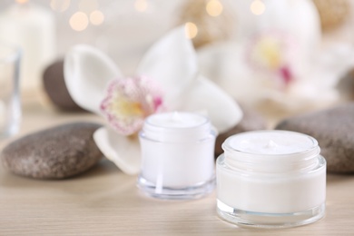 Beautiful composition with cosmetic products, spa stones and flowers on table, closeup. Space for text