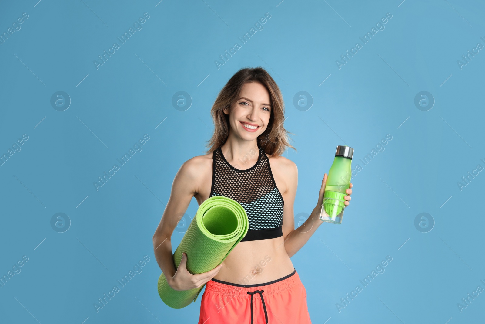 Photo of Beautiful woman with yoga mat and bottle of water on turquoise background