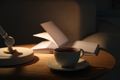 Photo of Cup of tea and book on side table indoors